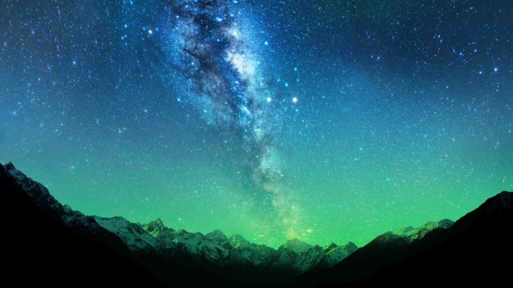 A starry sky above a mountain landscape at night.