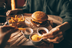 A table with a hamburger, fries, and dipping sauces.
