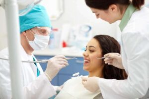 A dentist and her assistant evaluate a woman's teeth.