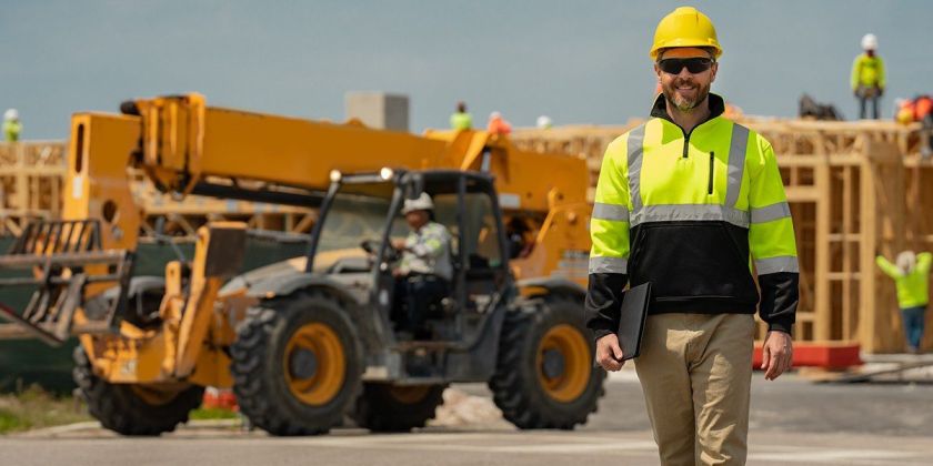 Blog 29 A worker in a high-vis jacket and hard hat walks away from an excavator.