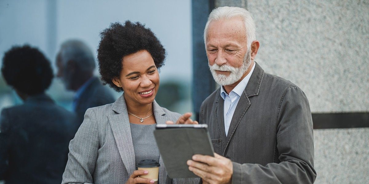 Blog 19 An older man and a woman in business attire looking at HR integration platform cost.