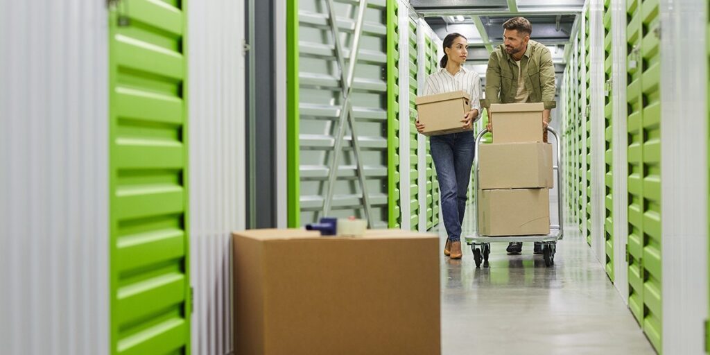 A woman carries boxes through the corridor of a storage facility.