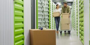 A woman carries boxes through the corridor of a storage facility.