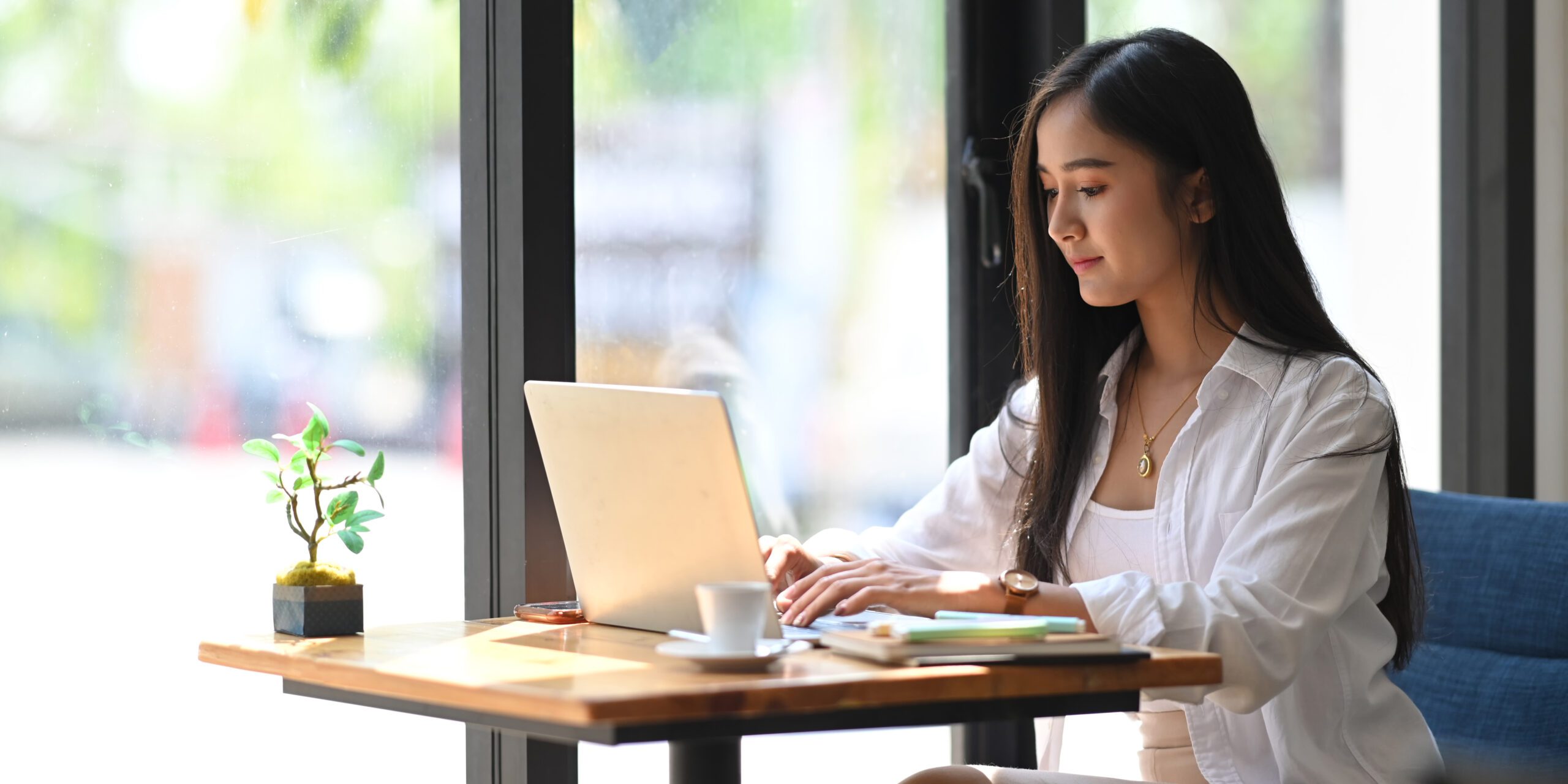 young woman working on computer at a coffee table