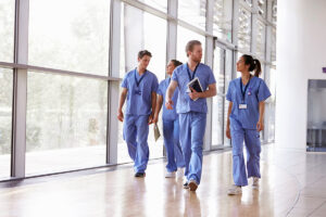 Four healthcare workers in scrubs walk down a hallway