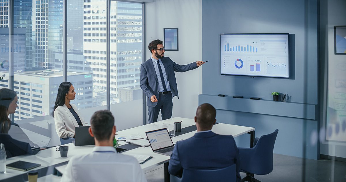 A businessman gives a presentation to a table of people.