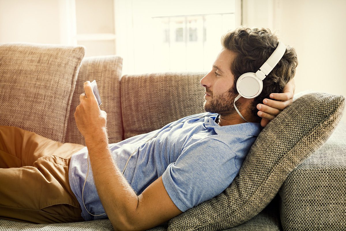 Man on couch watches a movie on mobile phone