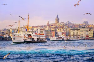 A boat moves across the water with the skyline of Istanbul in the background.