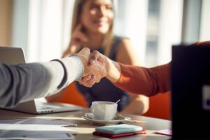 Two hands shake over a coffee table.