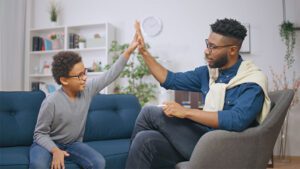 A boy and a psychologist high-five each other excitedly.
