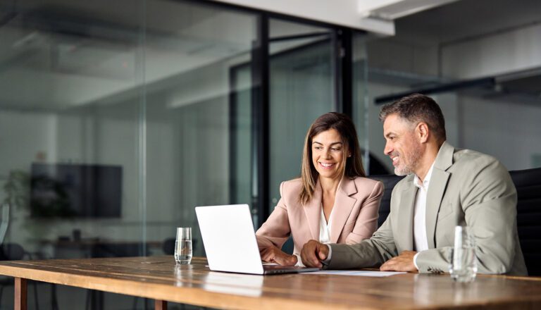 ADP to AD Integration 6 Two middle-aged businesspeople sit at a desk and participate in a video call on a laptop.