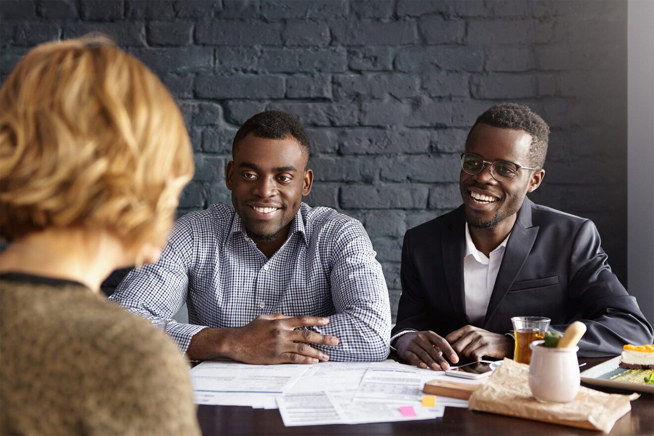 Two African American men in business attire interview a woman. Their organization's onboarding is smooth and easy thanks to Hire2Retire's Workday integration.