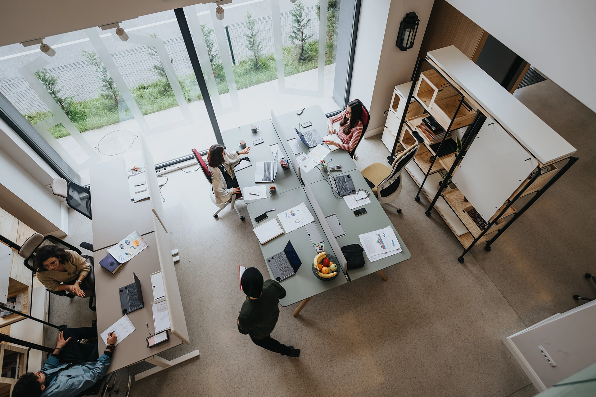 Blog 25 An overhead view of employees working at a desk in an office. Their company uses Hire2Retire’s PayMaster integration for employee onboarding automation.