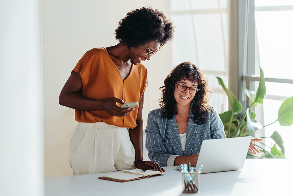 Blog 29 Two female entrepreneurs using a laptop for a productive business meeting in a corporate workplace.