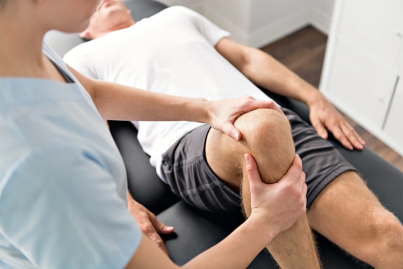 An orthopedic physician examines an athlete’s knee.