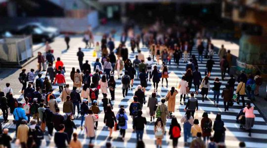 Lots of people walking down a busy city crosswalk.