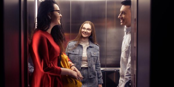 The girls and the guy ride in the elevator.