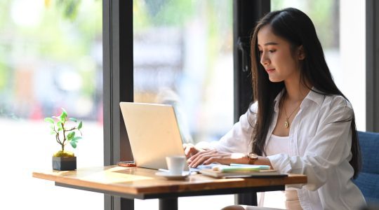 young woman working on computer at a coffee table