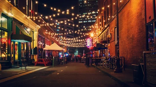 A city alleyway at night lit up with string lights, connecting buildings like Hire2Retire connects Infor HCM to Google Workspace.