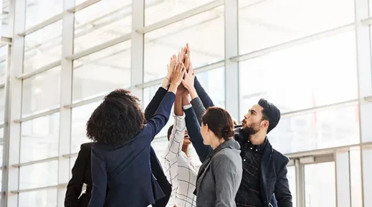 Happy colleagues high-fiving each other, they use Hire2Retire for HR to AD sync up