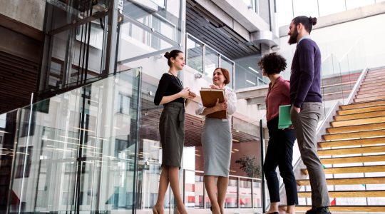 Group,Of,Young,Businesspeople,Standing,Near,A,Staircase,,Talking.