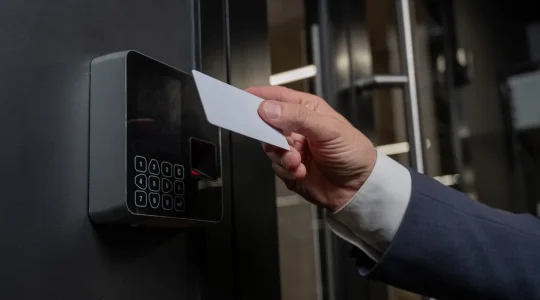 A person holds a keycard to a scanner outside an office building. With Hire2Retire automating resource provisioning, they can only access the systems crucial to their job.
