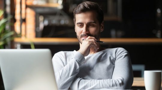 Businessman sitting at desk reading his computer screen.