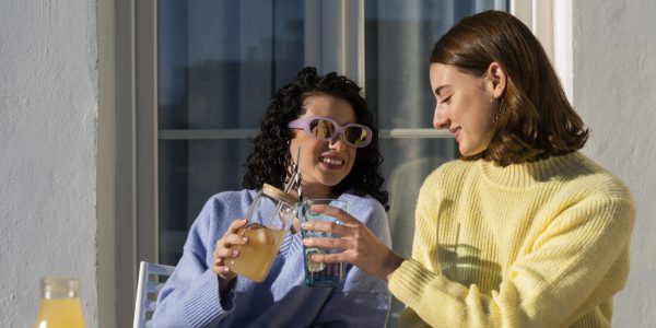 Two young ladies enjoy drink in sunlight.